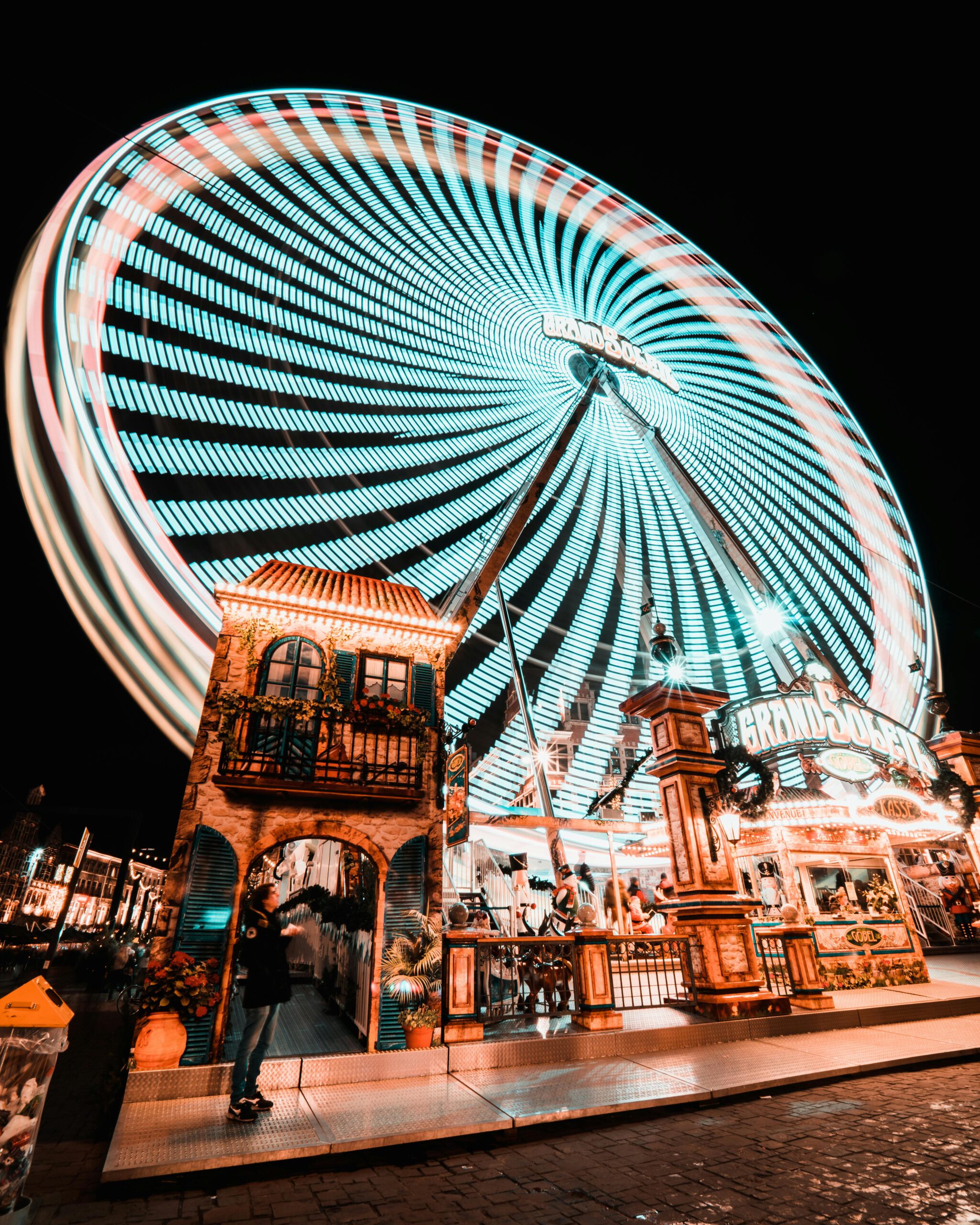 Long exposure of a colorful Ferris wheel spinning at a festive night carnival.